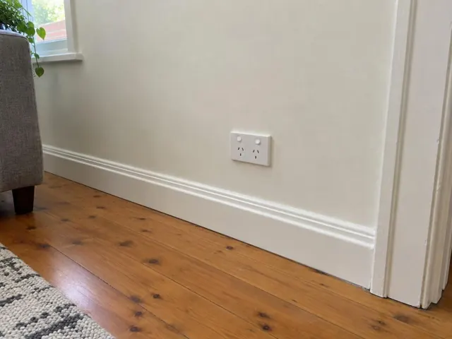 White double power point on a painted wall above timber floorboards and skirting in Waratah