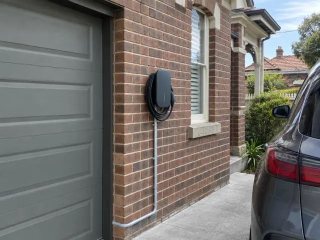 EV charger mounted on a brick exterior wall beside a garage and driveway in Georgetown